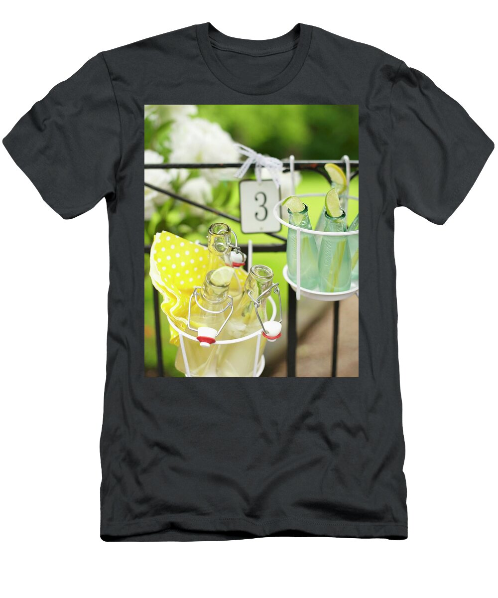 Bottles of Lemonade in Wire Basket Hung on Garden Fence Hannah Kompanik T-Shirt