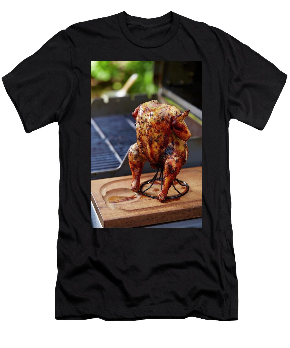Grilled Jerk Chicken on a Stand in Front of a Barbecue Leigh Beisch T-Shirt